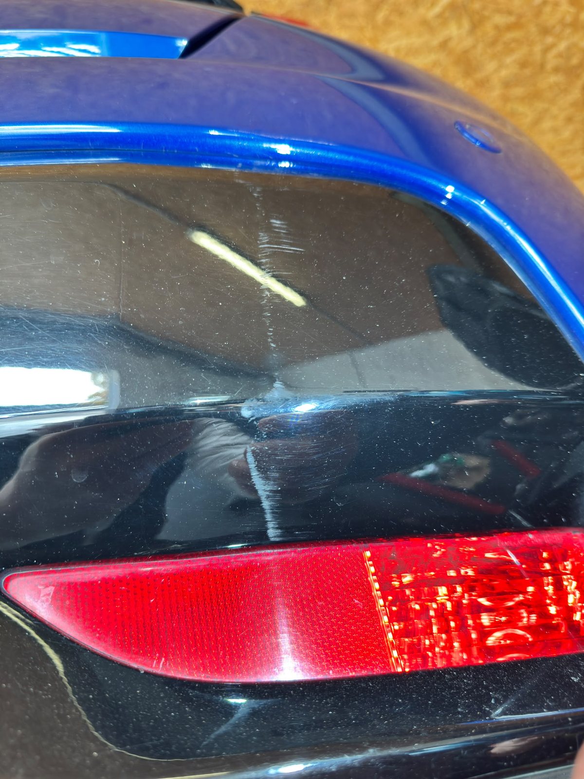 Detailaufnahme des Heckstoßfängers oberhalb des Reflektors mit feinem Kratzer im Lack