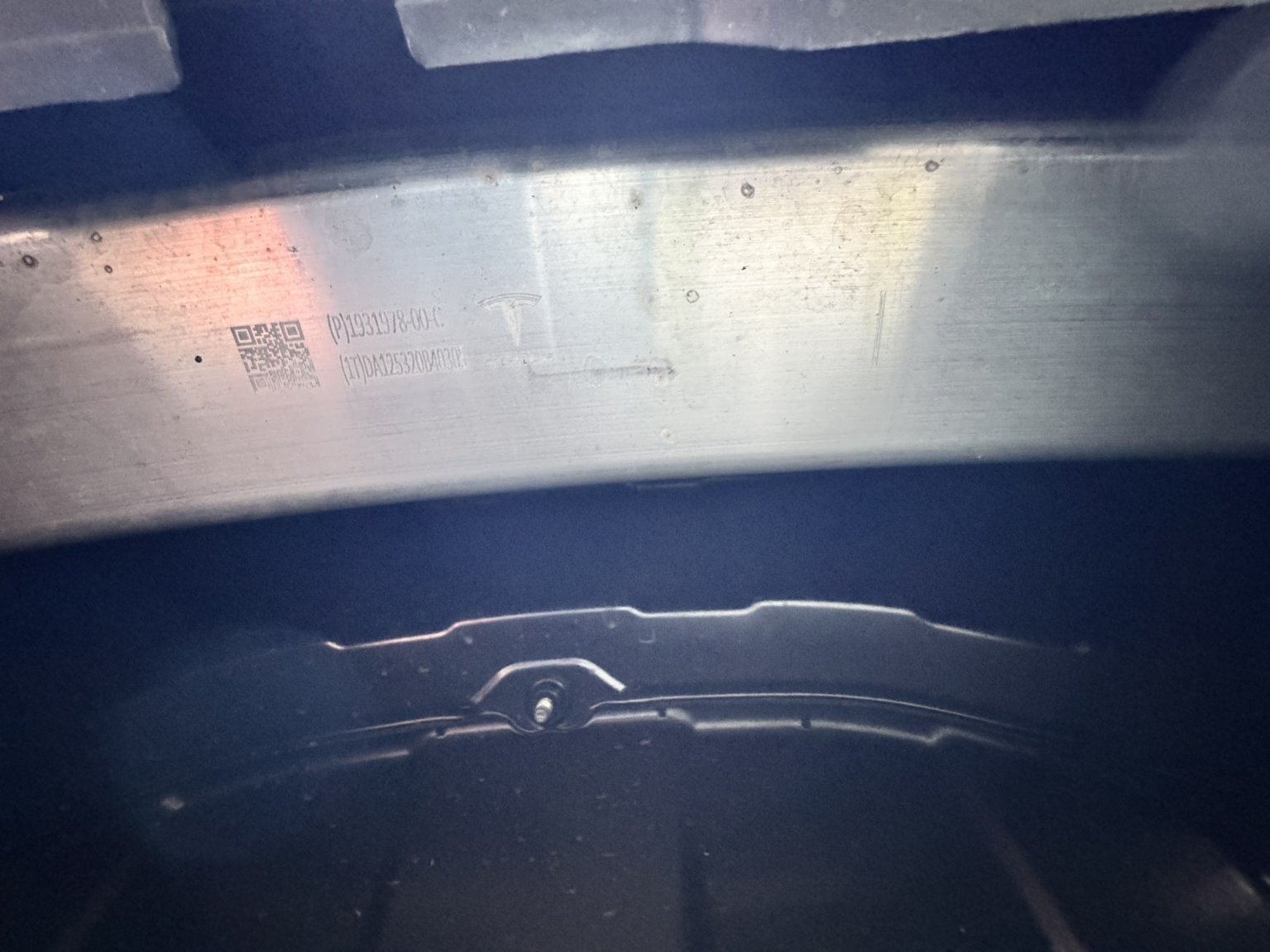 Blick in den Heckbereich von unten auf Aluminiumträger und Verkleidung des Tesla Model Y